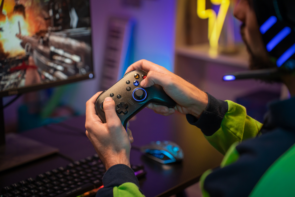 Gamer hands playing with joystick on green screen in trendy and stylish room with neon light. Streaming video games concept. High quality POV photo