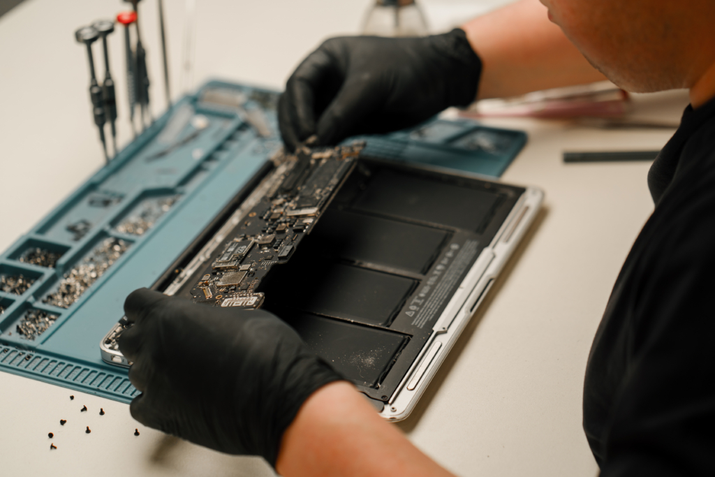 Technician engineer repairs or replaces new parts of broken and damaged laptop and tablet Workshop for repair of telephones and equipment computer boards and processors